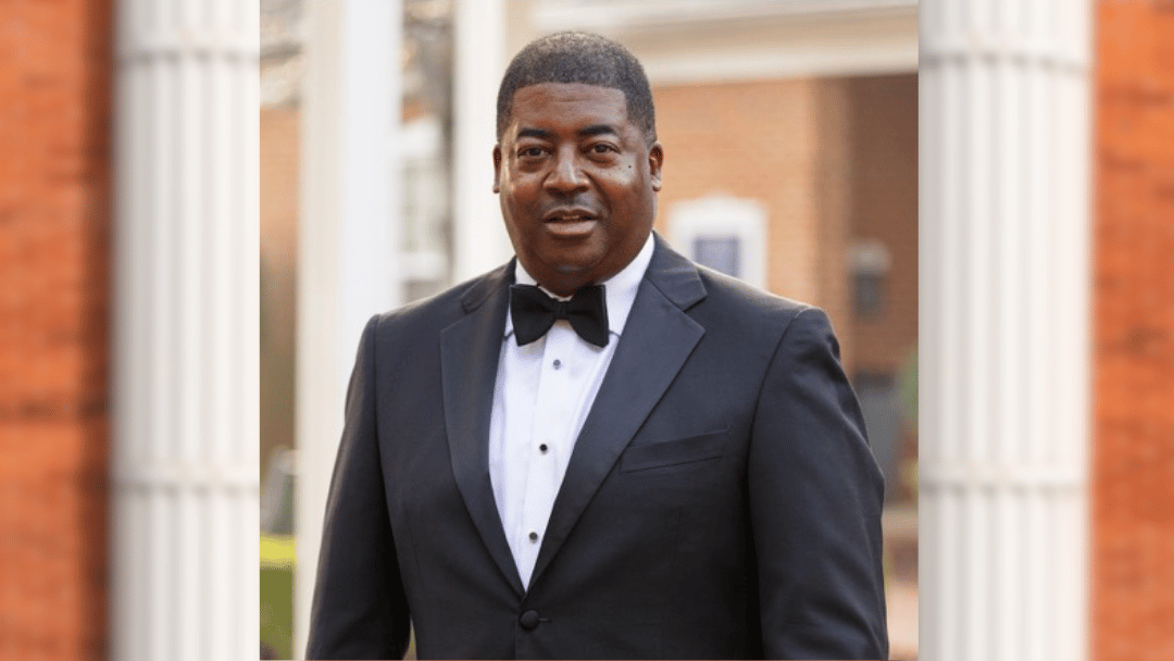 Damion Womack Damion Womack in black tuxedo, standing in front of brick building with columns